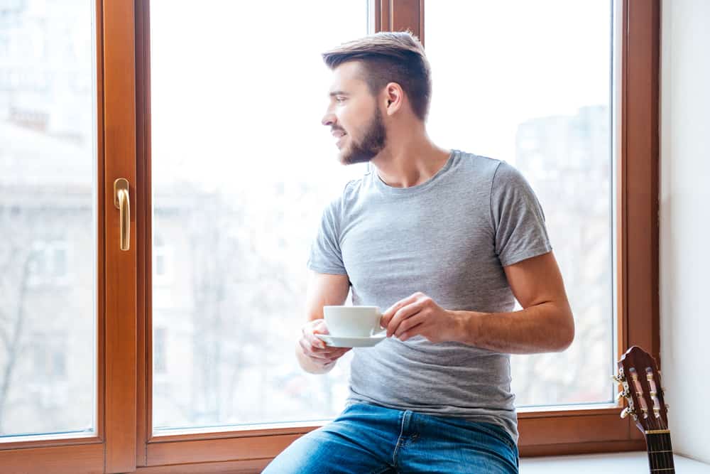 un homme est assis près de la fenêtre et boit du café