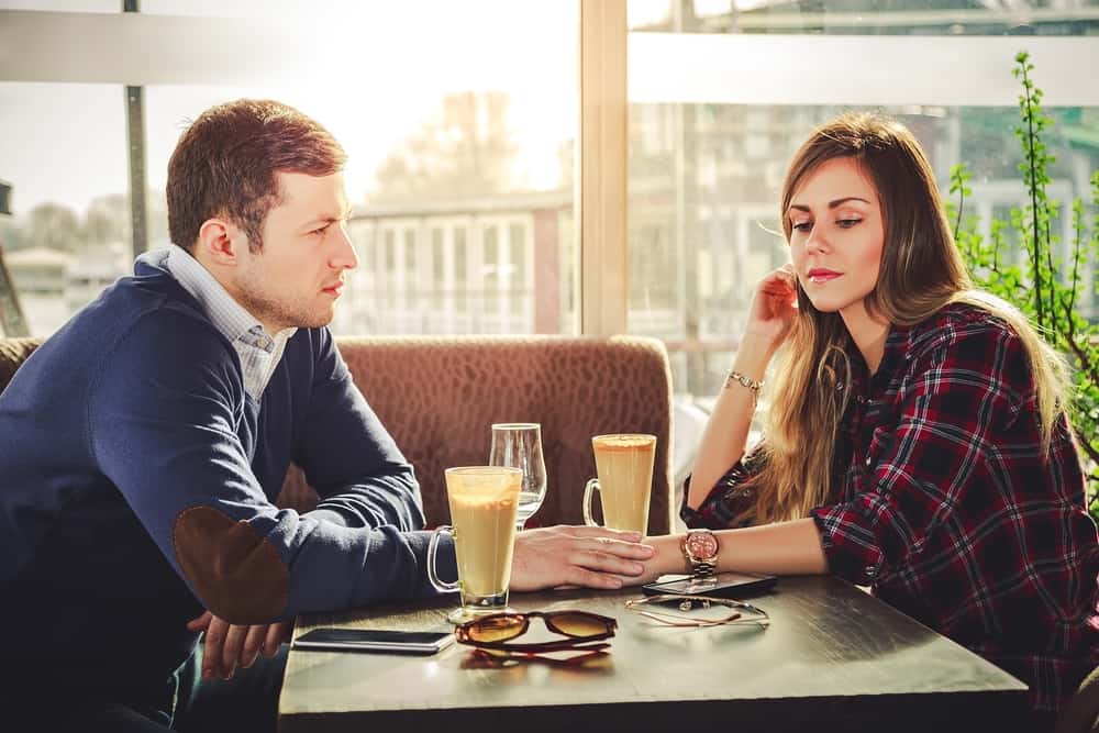 un homme et une femme assis à une table il touche sa main