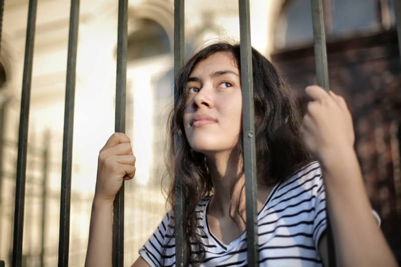 une femme réfléchie regarde à travers la clôture