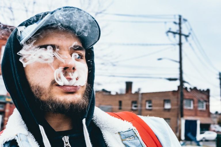homme exhalant de la fumée à l'extérieur