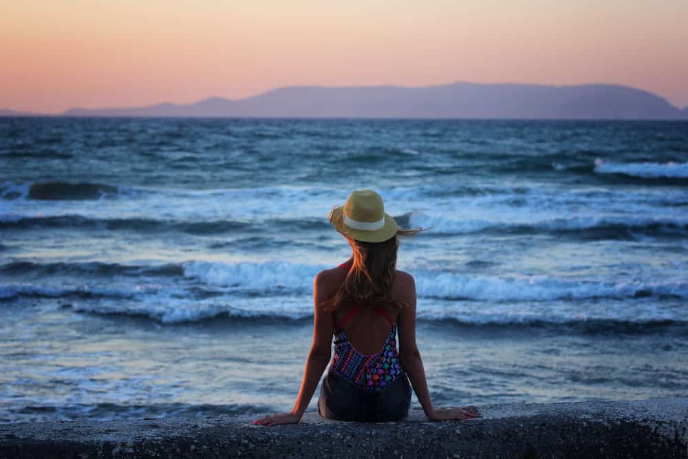 Une femme assise en bikini à côté de la plage avec le dos tourné