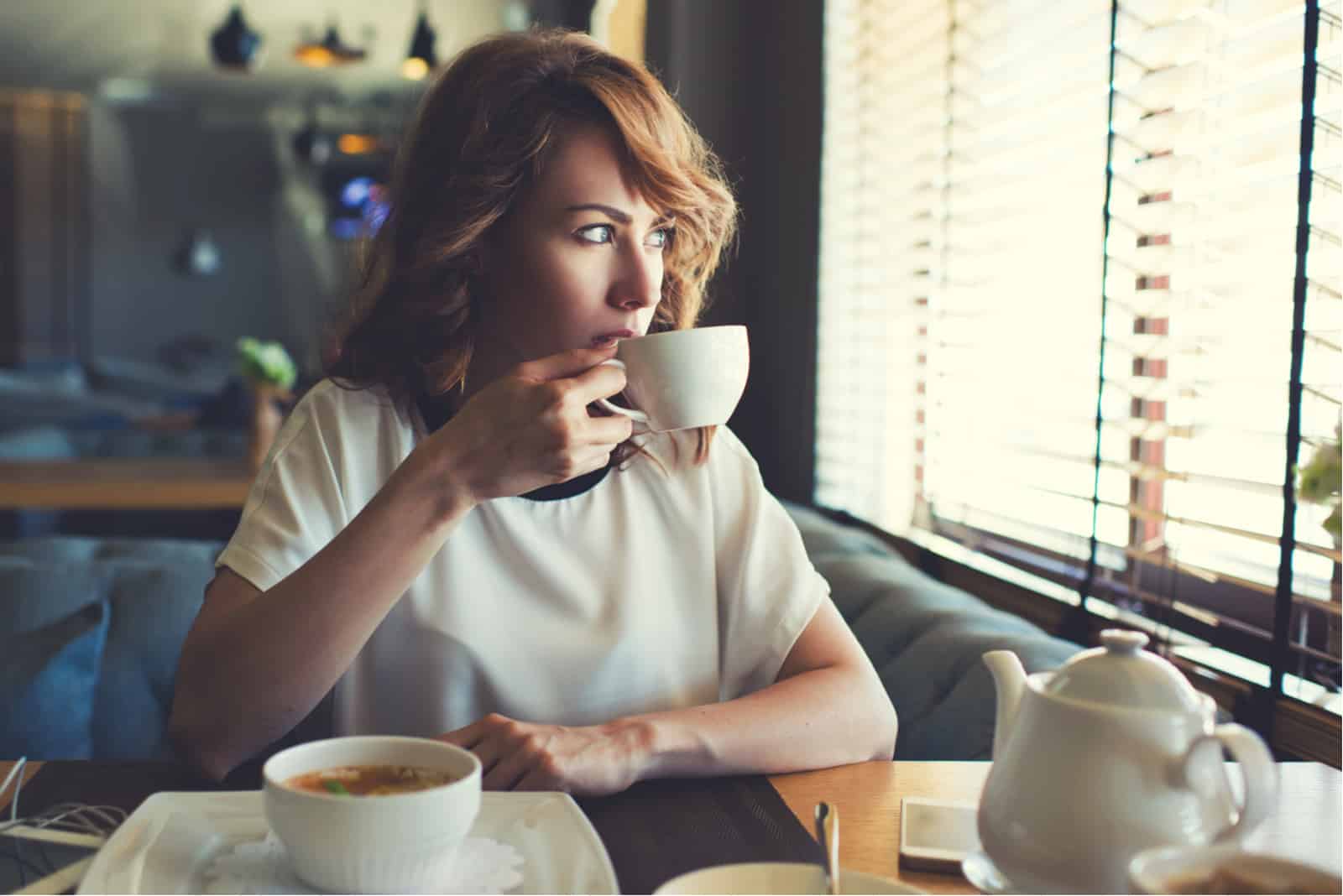 femme assise seule dans un café buvant du café