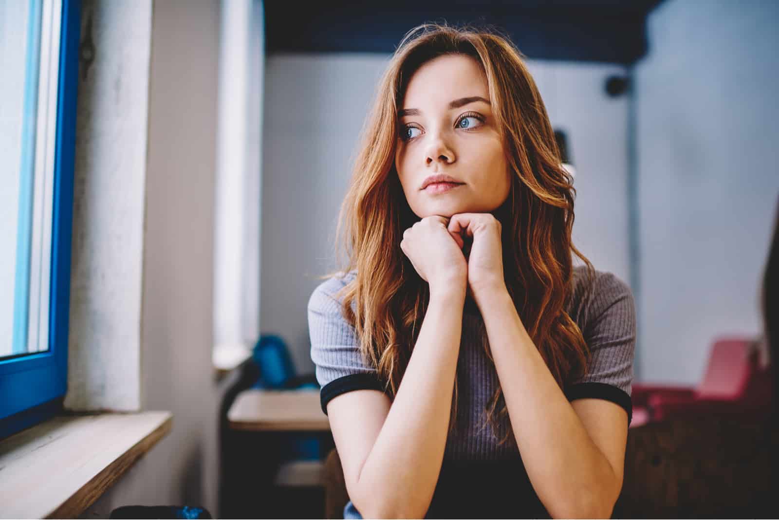 pensive belle femme regardant par la fenêtre