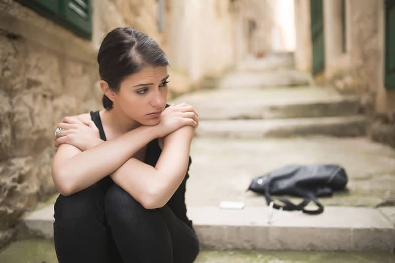 triste jeune femme assise sur un escalier dans une ruelle