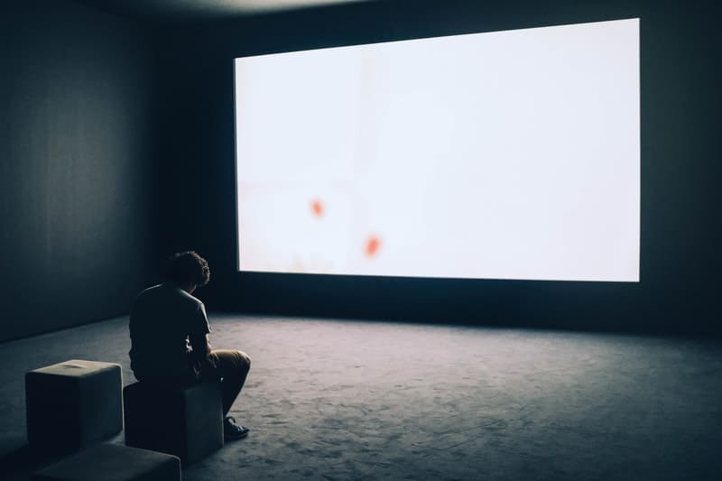 un homme assis devant un grand écran