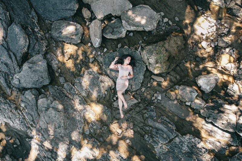 une femme en robe se trouve sur un rocher