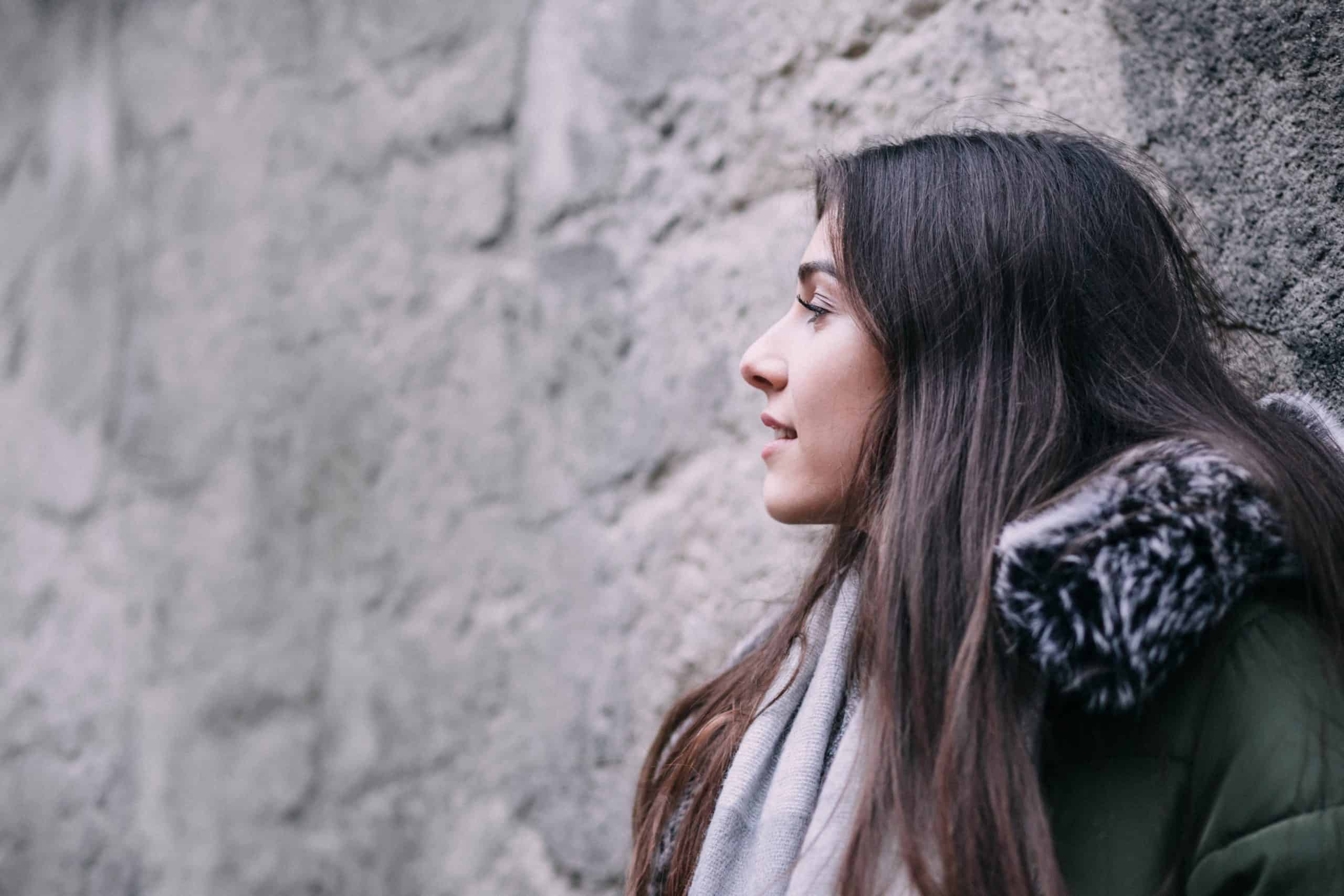 une femme heureuse se tient près du mur