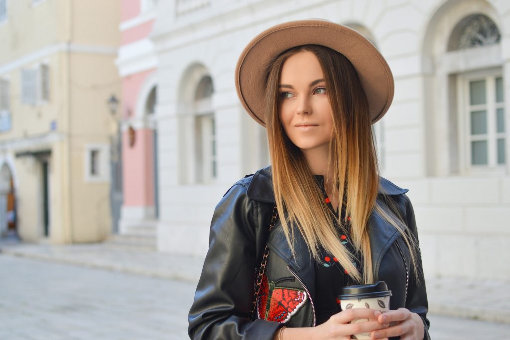 une femme imaginaire avec un chapeau sur la tête tient du café à la main