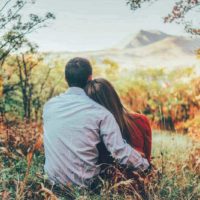 une femme et un homme embrassent assis sur l'herbe