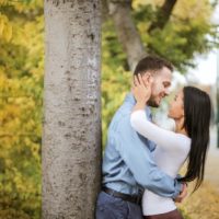 un homme et une femme s'embrassant près d'un arbre