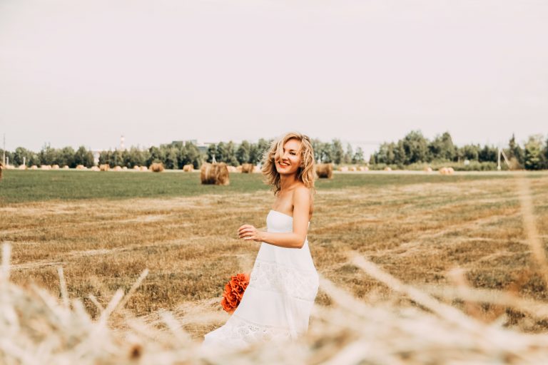 Une femme souriante dans un champ brun