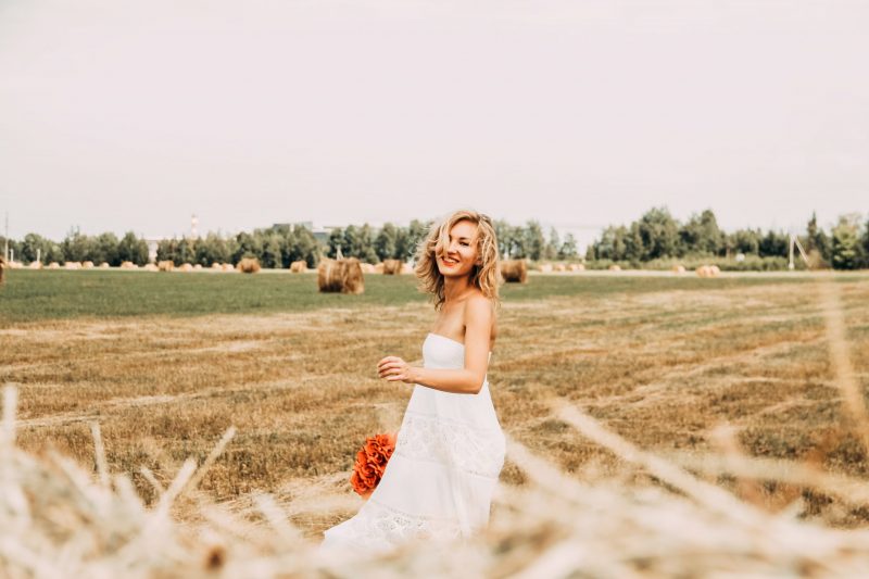 Une femme souriante dans un champ brun