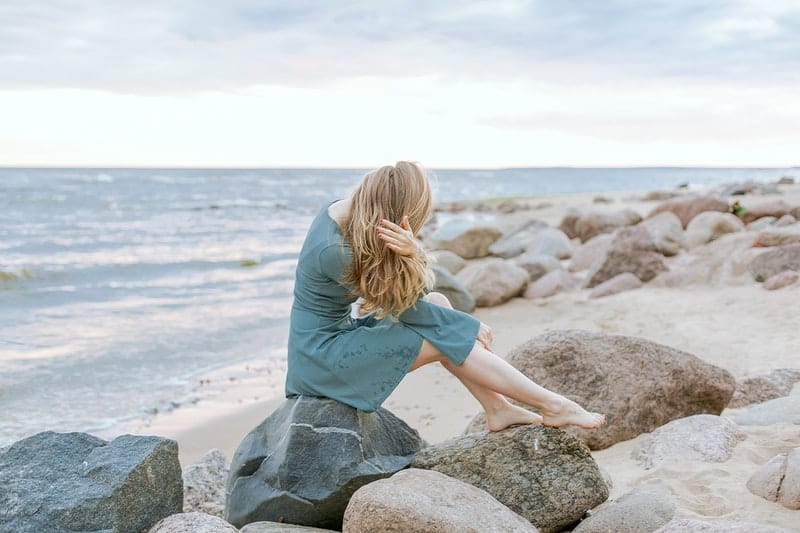 femme assise sur des rochers près de la mer