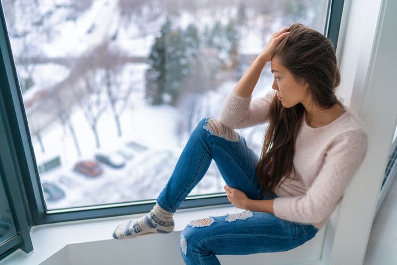 jeune femme triste par la fenêtre