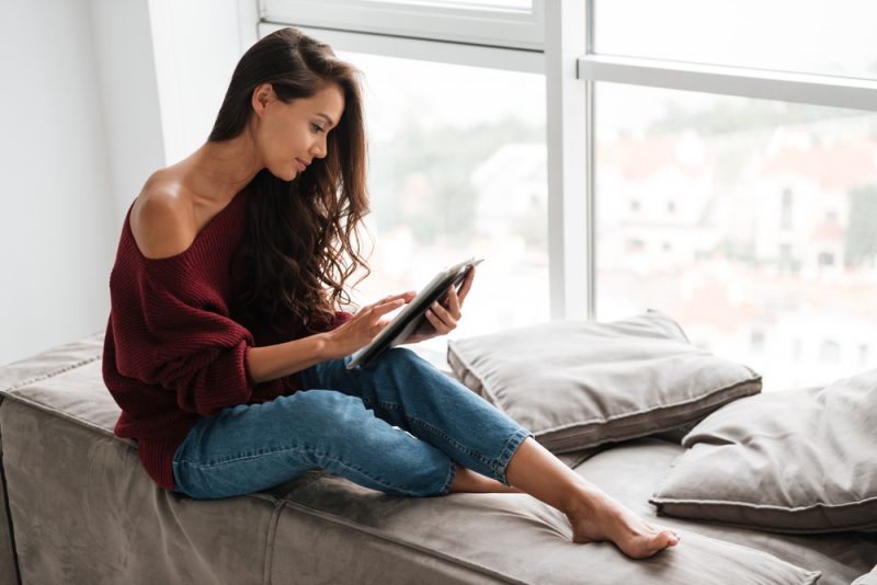la femme est assise avec une tablette à la main