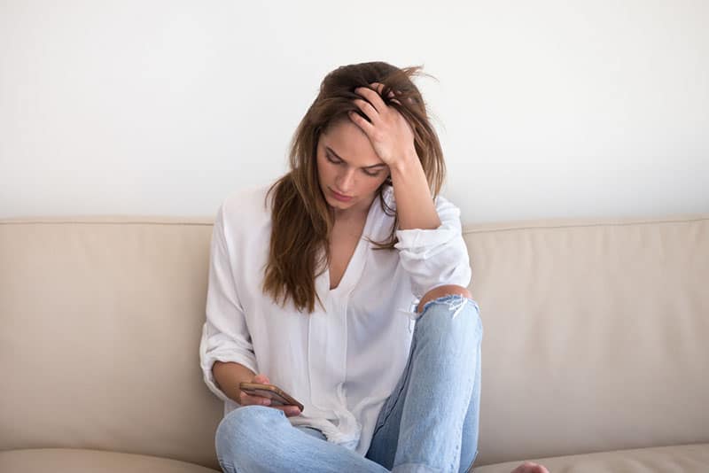 triste jeune femme assise sur le canapé
