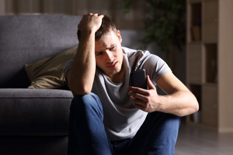 un homme déçu regarde le téléphone
