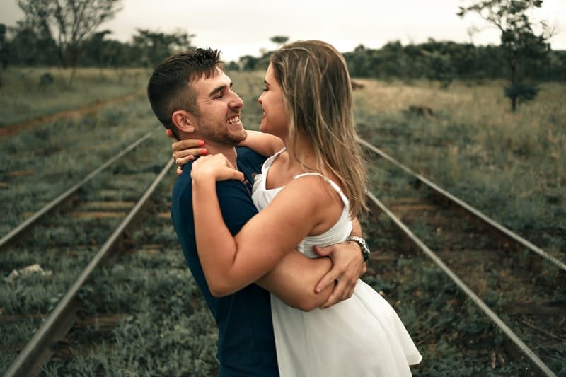 un homme embrasse une femme par les voies ferrées