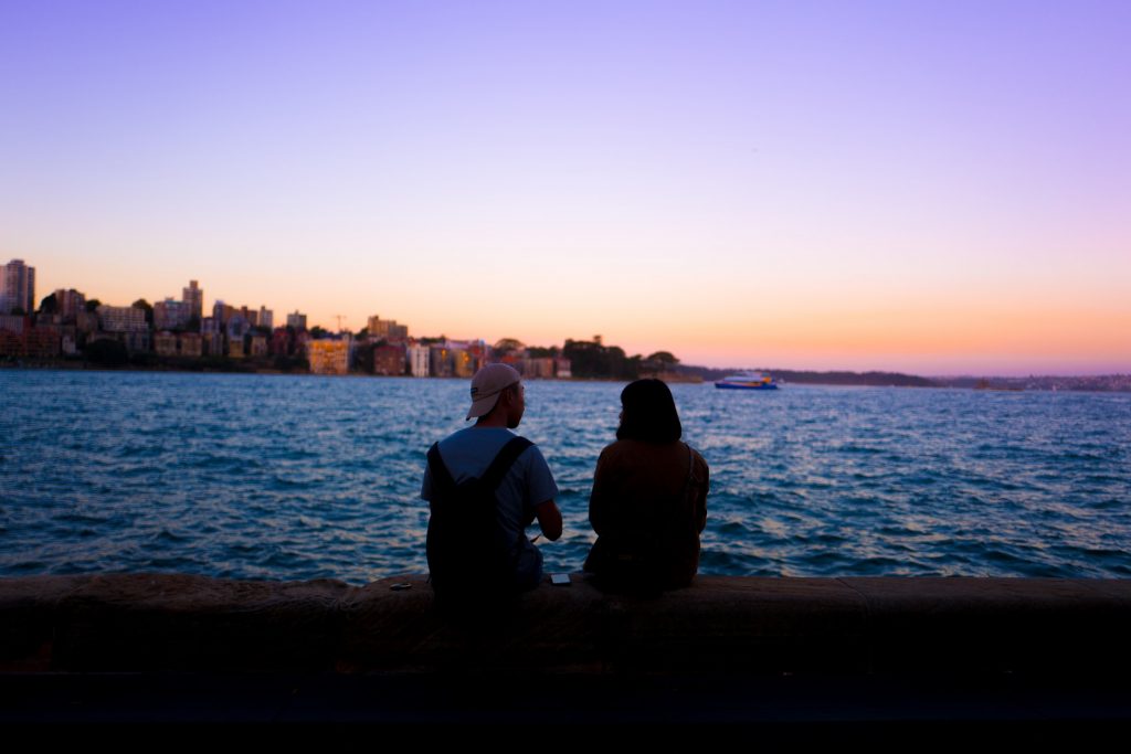 un homme et une femme s'assoient au bord de la mer et parlent