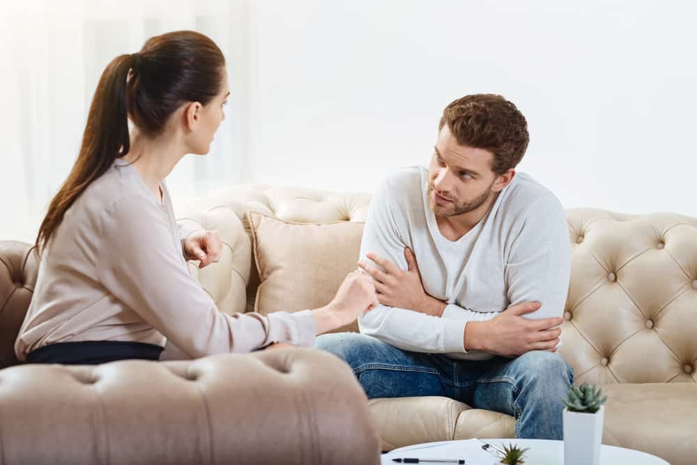 un homme et une femme s'assoient sur le canapé et parlent