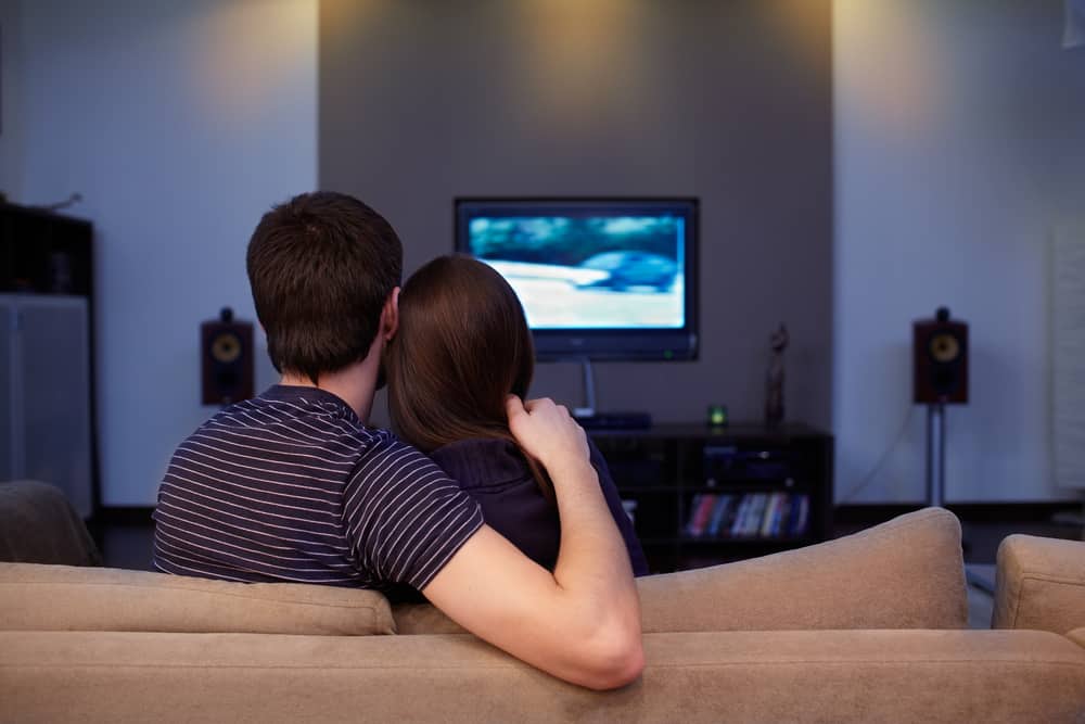 un homme et une femme sont assis devant la télé