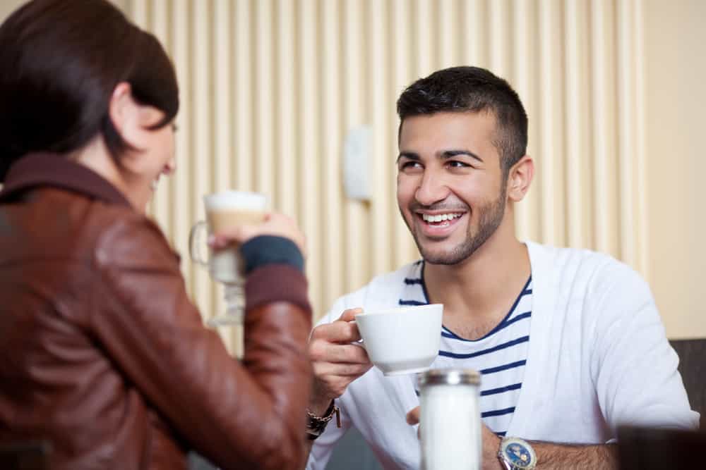 un homme et une femme sont assis en train de boire du café et de rire