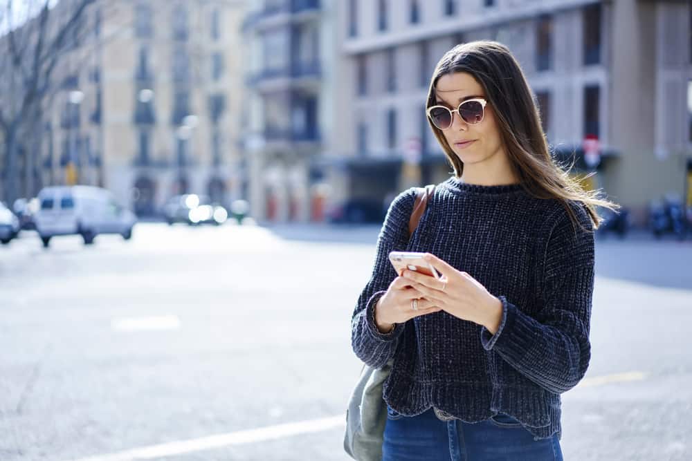 une femme avec des lunettes définit et écrit sur le téléphone