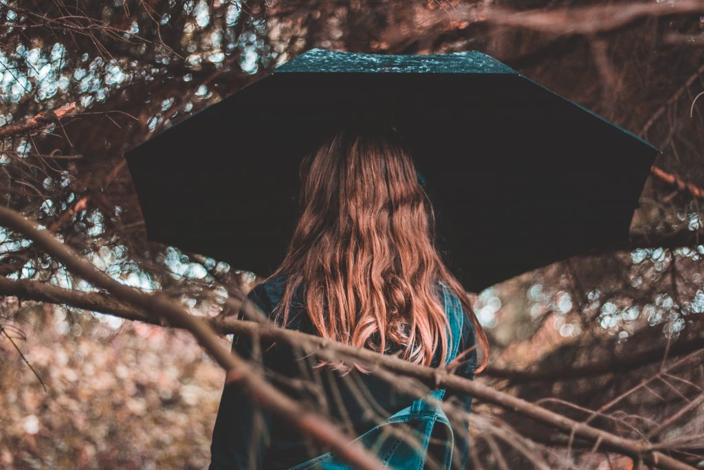 une femme avec un parapluie noir sous la pluie