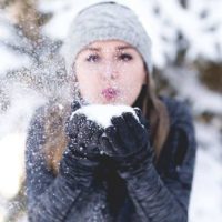 la femme souffle la neige de sa main