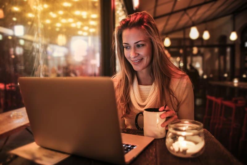 Une femme blonde avec du sel dans sa main est assise derrière un ordinateur portable