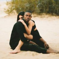 un homme et une femme assis sur la plage embrassant