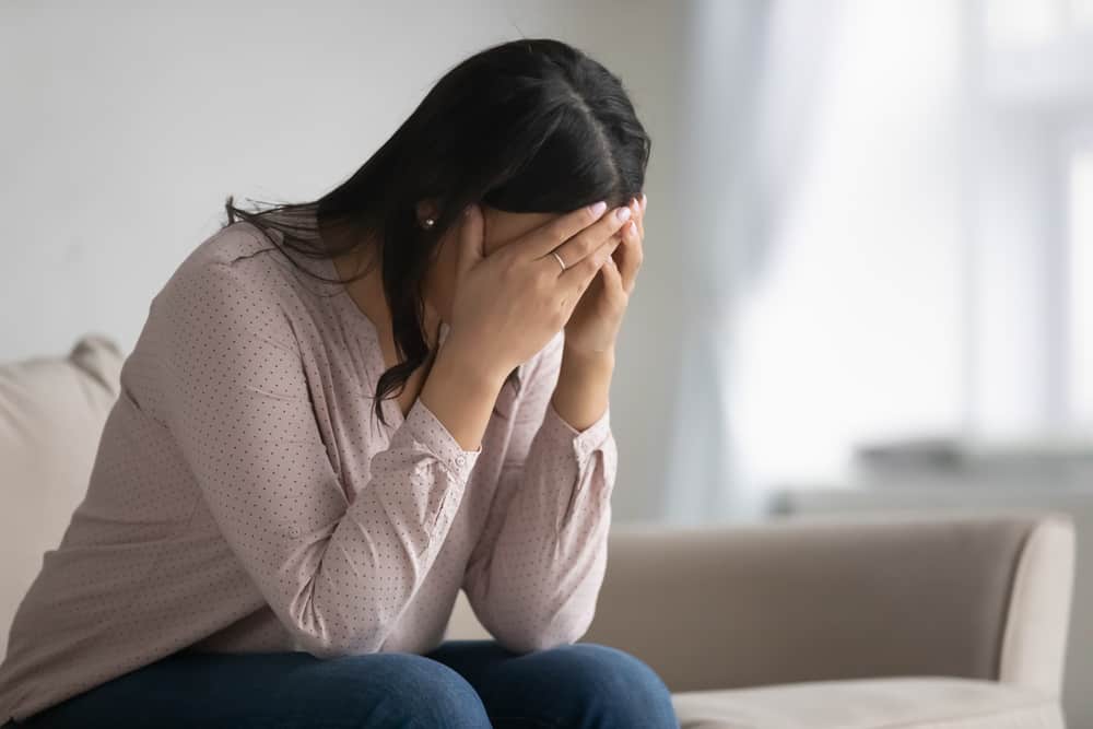 la femme est assise sur le canapé avec la tête baissée