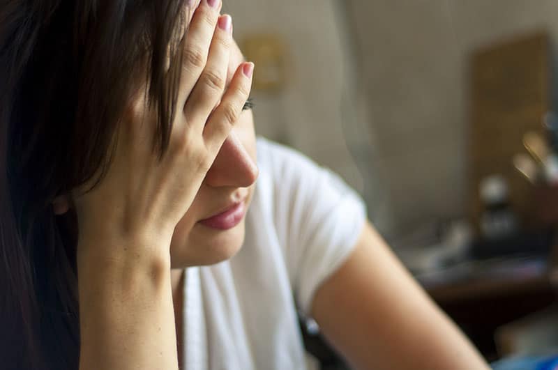 triste jeune brune avec sa main couvrant sa tête