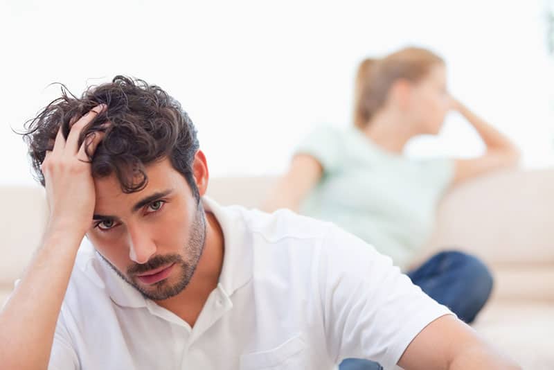 triste jeune couple assis sur le canapé