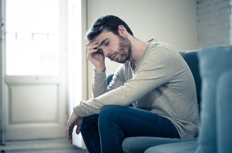 triste jeune homme assis sur un canapé