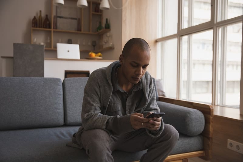 un homme appuie sur le téléphone et s'assoit sur le canapé