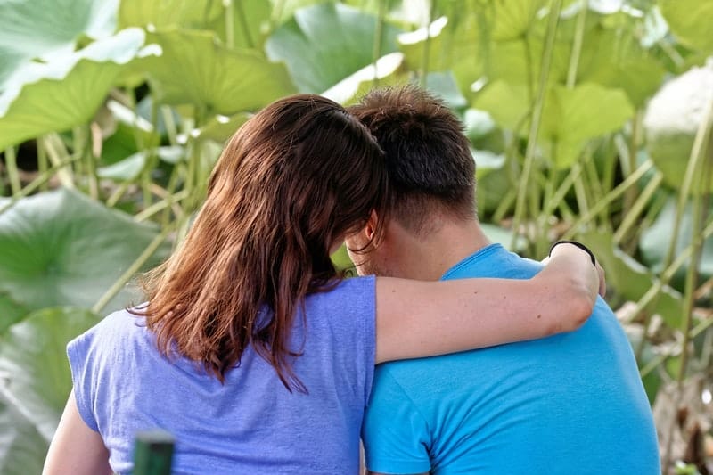 un homme et une femme câlin sous un arbre