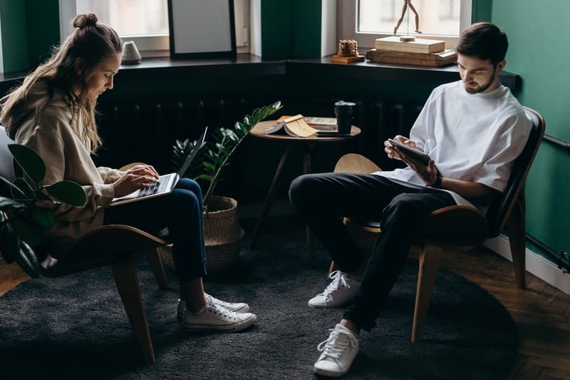 un homme et une femme parlant à côté d'ordinateurs portables