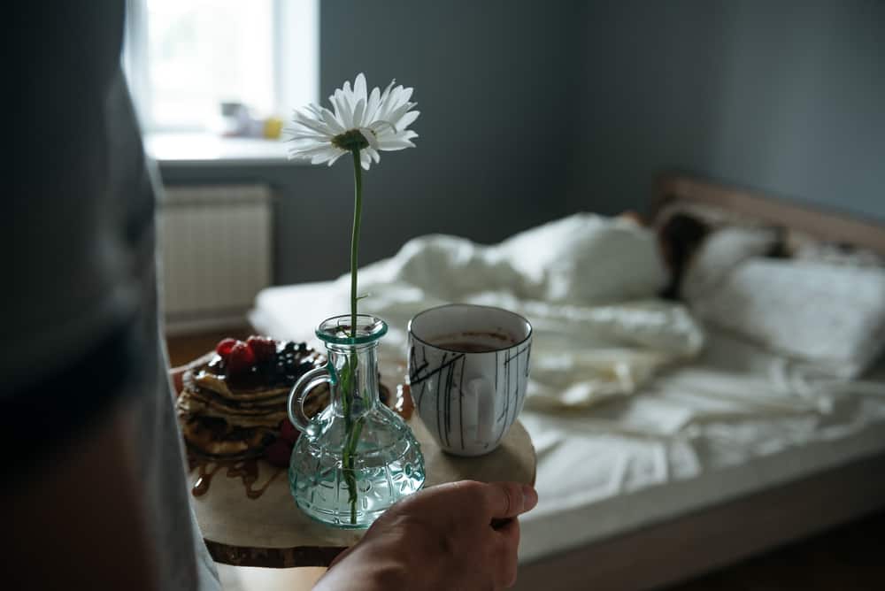 un homme porte le petit déjeuner à une femme au lit