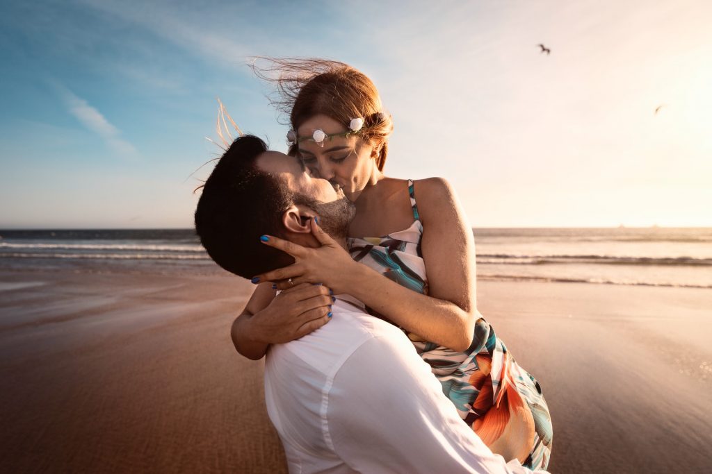 un homme porte une femme et l'embrasse sur la plage