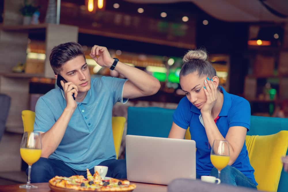 une femme assise devant un ordinateur portable un homme parlant au téléphone
