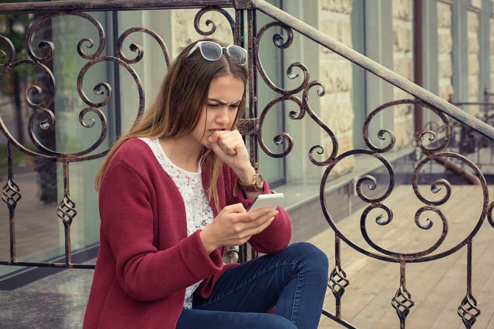 une femme assise sur les escaliers avec un téléphone à la main