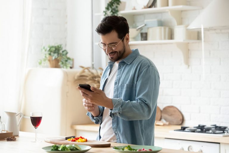 jeune homme prépare le dîner et envoyer des SMS