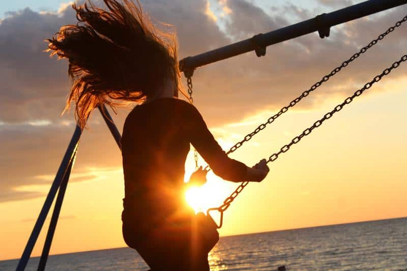 femme sur une balançoire coucher de soleil