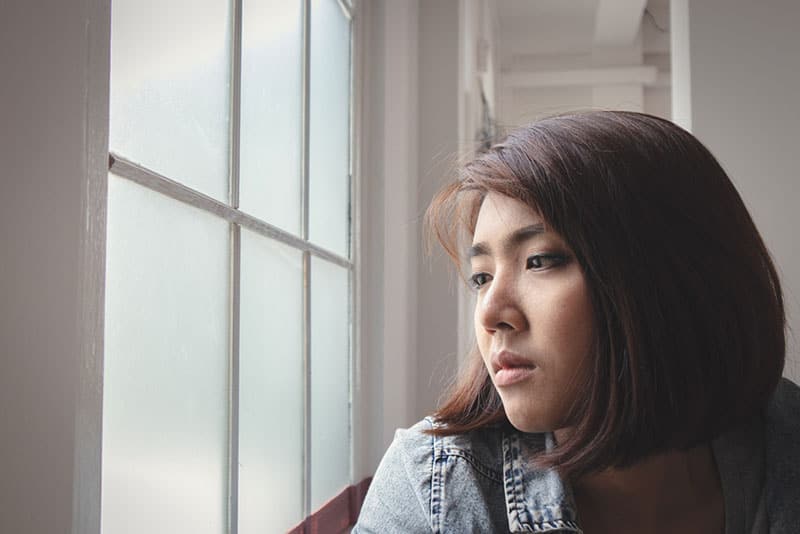 gros plan d'une triste femme asiatique par la fenêtre