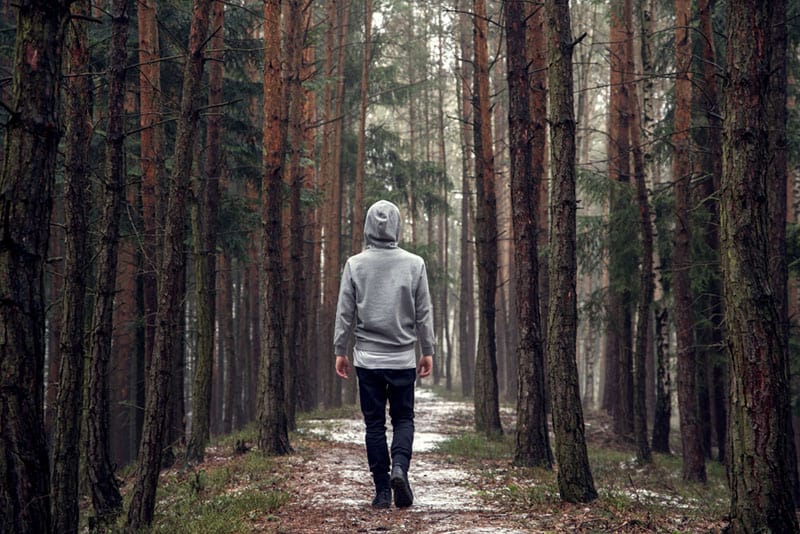 jeune homme à capuche dans la forêt