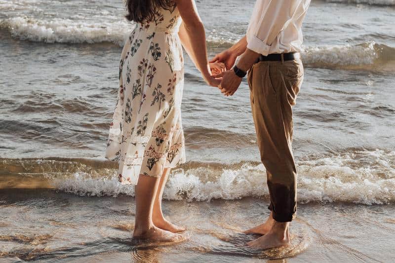 le couple se tenant la main au bord de la mer