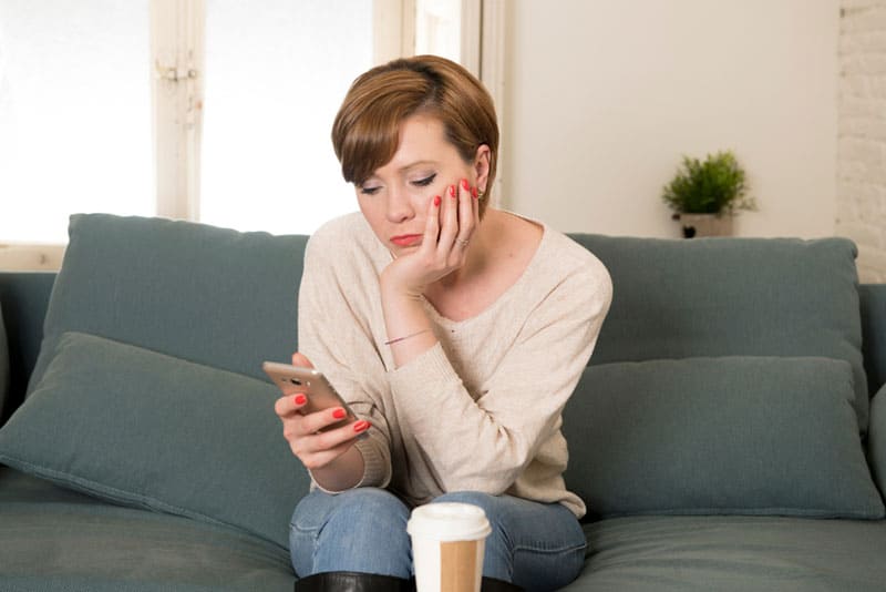 triste femme mature textos sur canapé