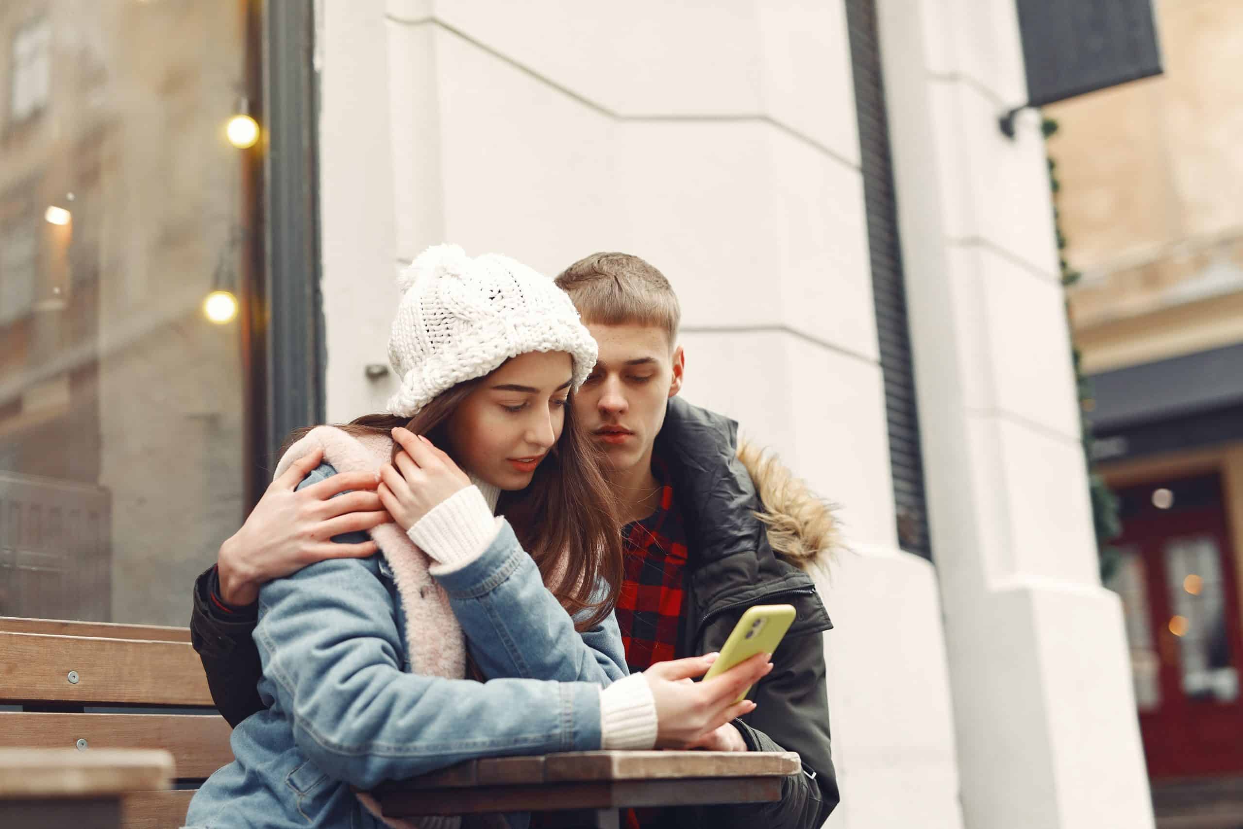 un homme est assis à côté d'une femme et elle tient un téléphone dans sa main