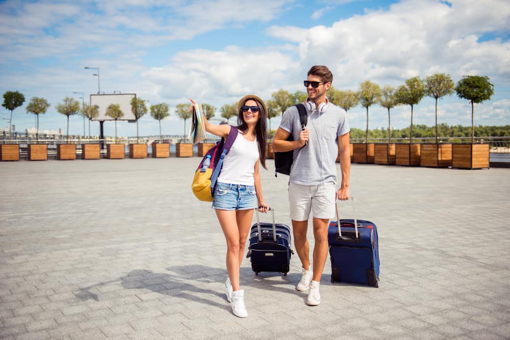 un homme et une femme marchent avec des valises